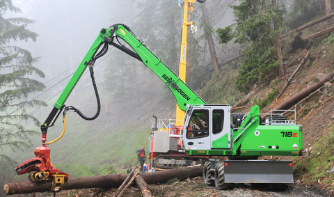 Combination of cable yarder and SENNEBOGEN material handler on a mountain side. The new SENNEBOGEN 718 E series fitted with a harvester head at work in the Pitztal valley for Lau Forstservice GmbH.